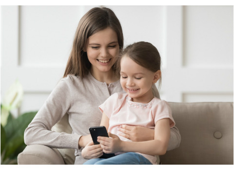 Young mom supervising daughter smartphone apps